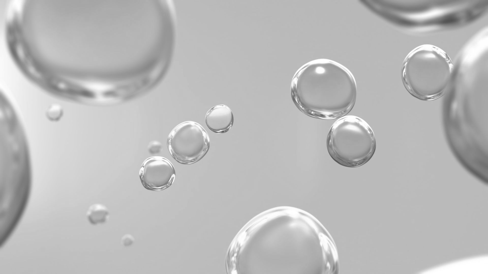 Floating, translucent water droplets against a light gray background.