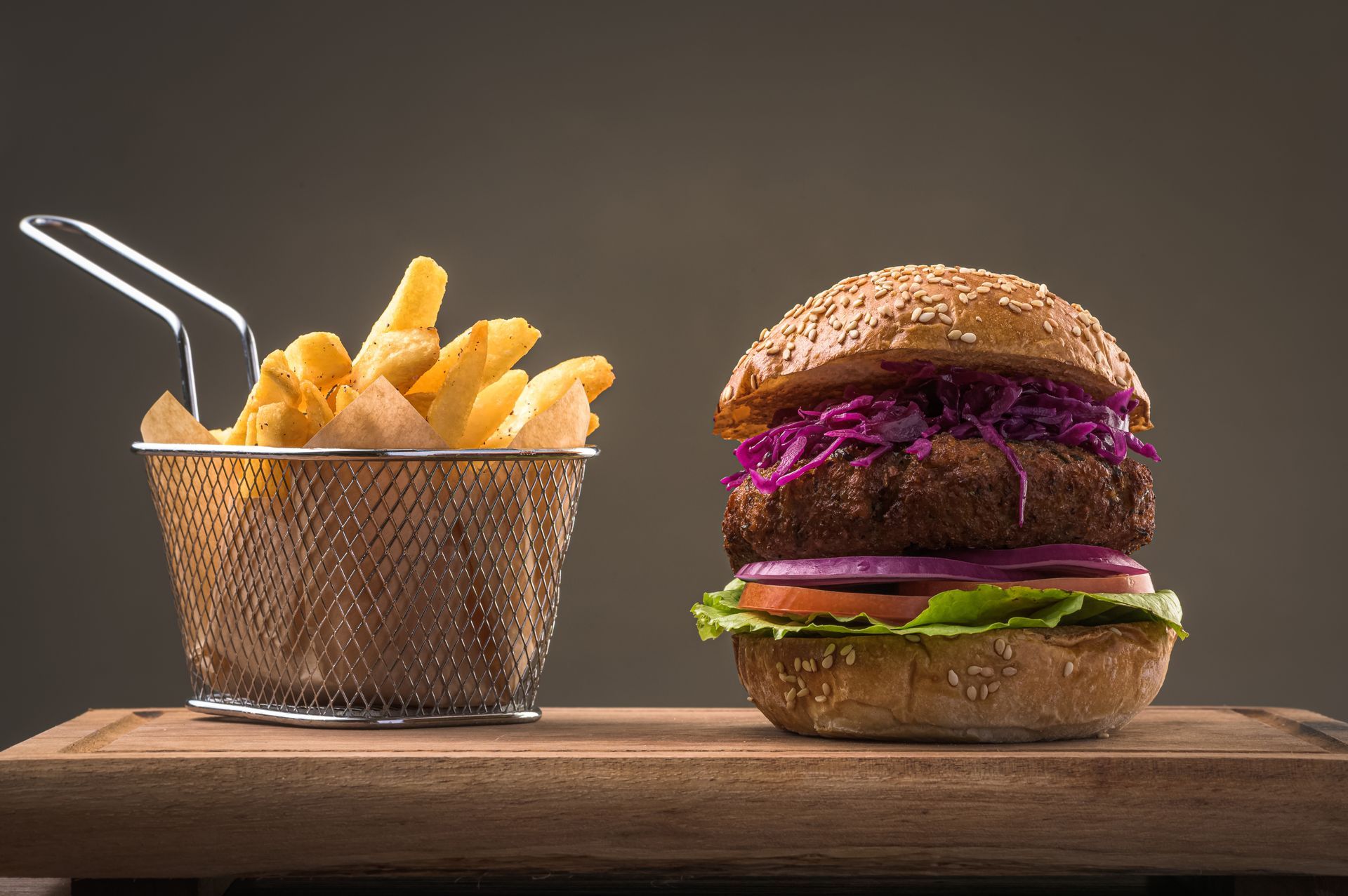 Una hamburguesa y papas fritas están en una tabla de cortar de madera.