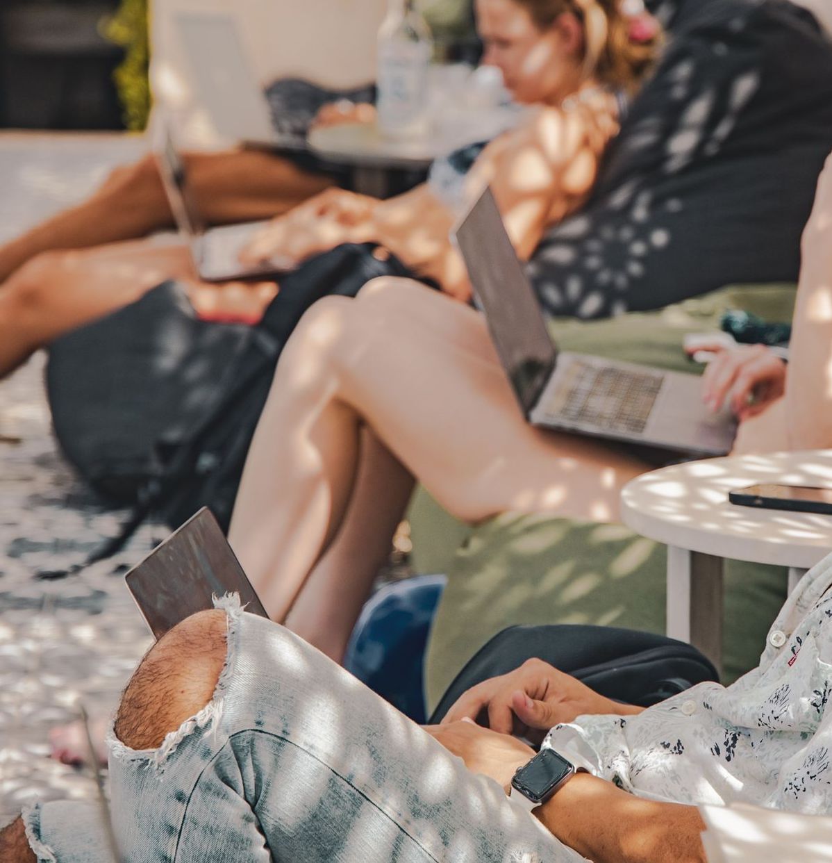 A group of people sitting on bean bags using laptops