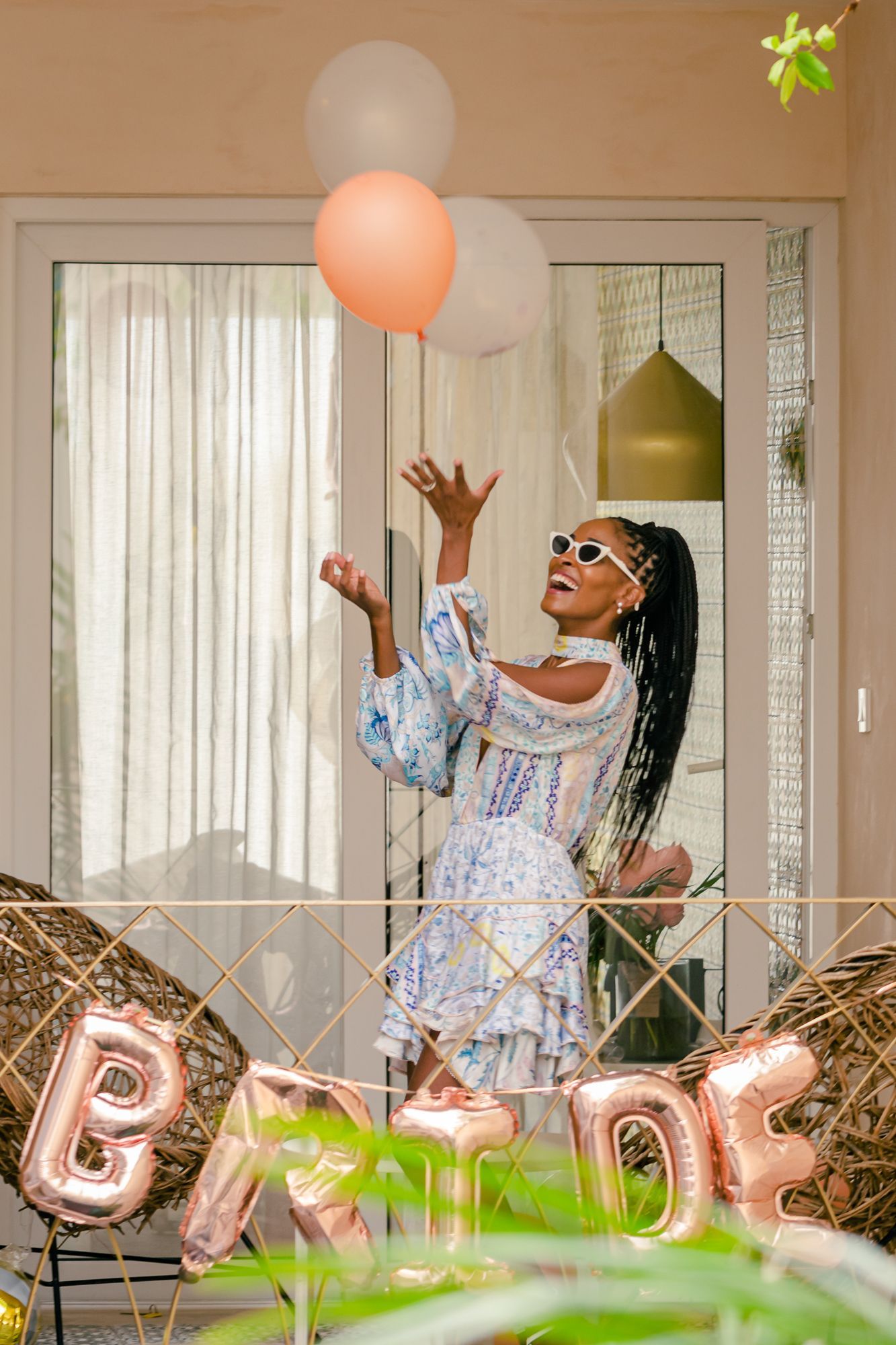 A woman in a white dress is throwing balloons in the air.