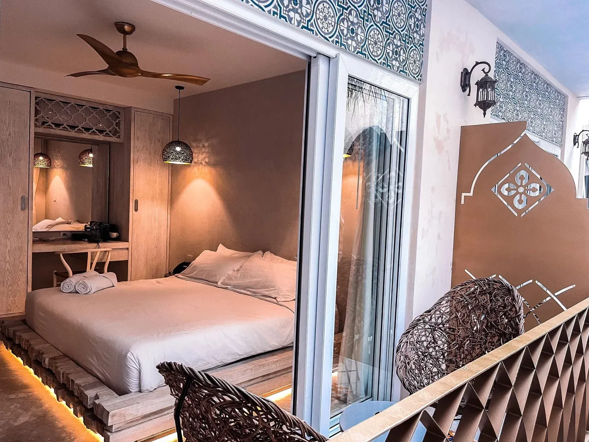 Bedroom with bed, closet, and balcony with intricate patterns.