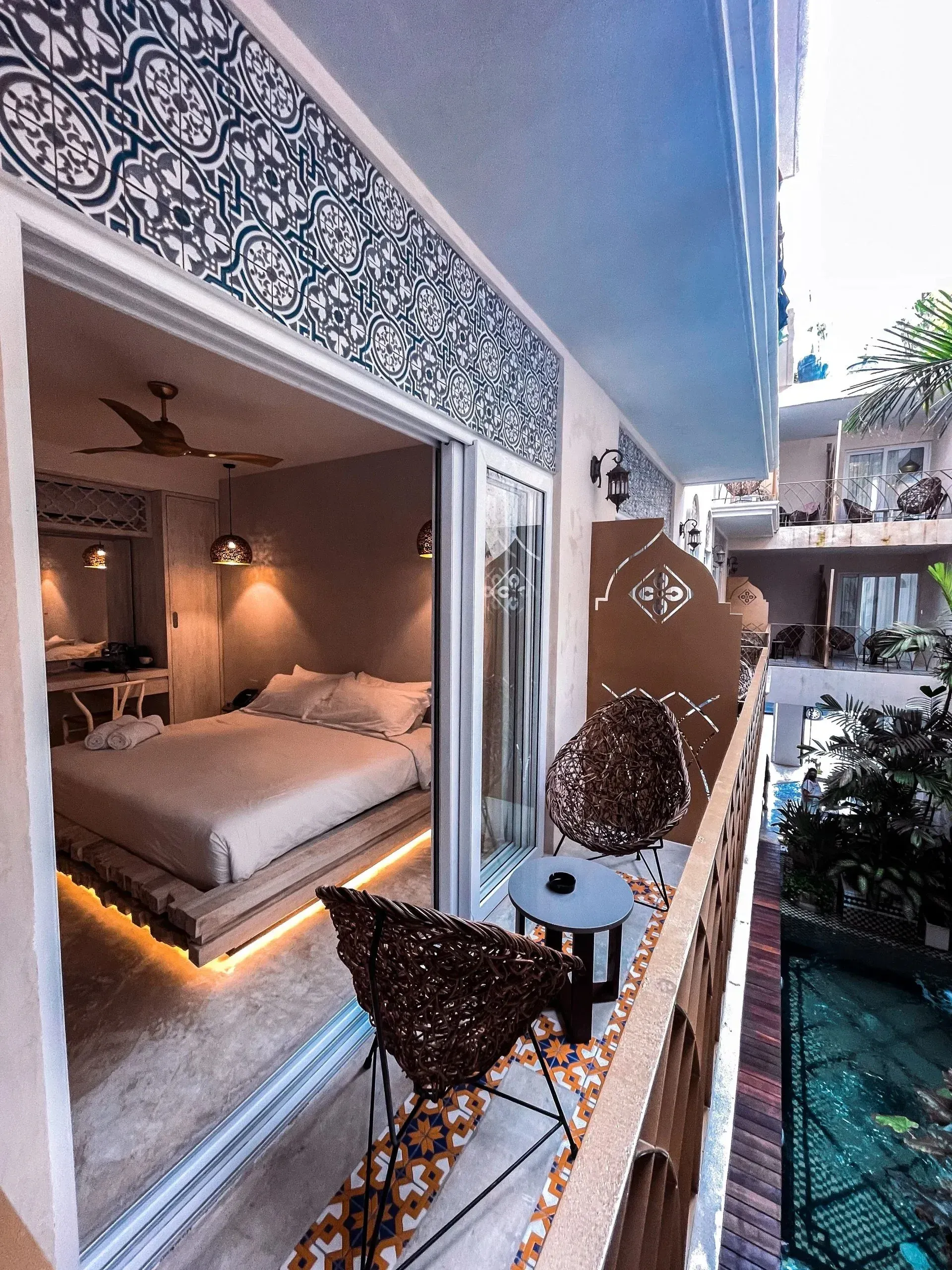 Balcony with patterned trim and seating, open to a bedroom with a bed.