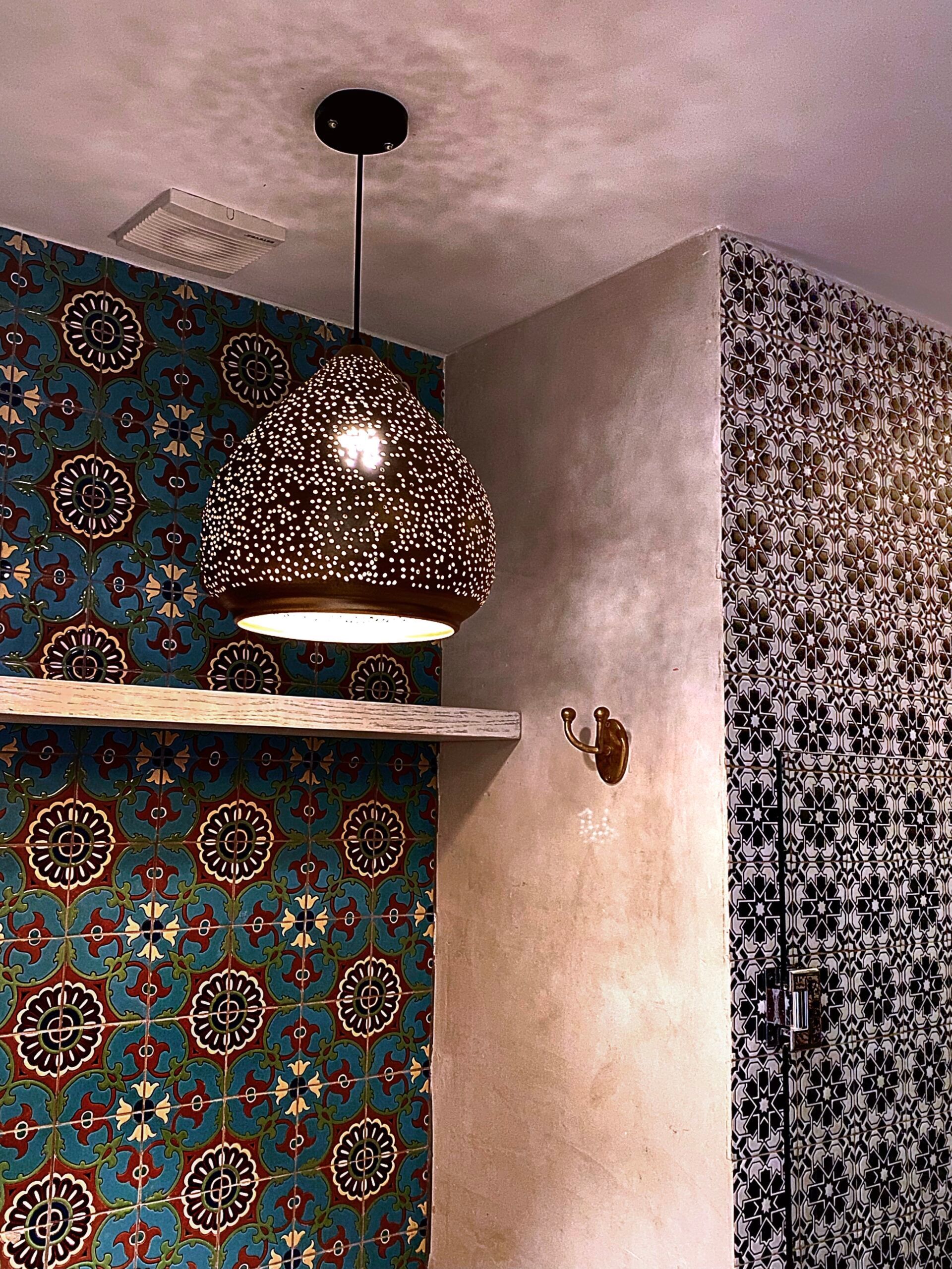 Un baño con una lámpara de techo colgando y un estante.