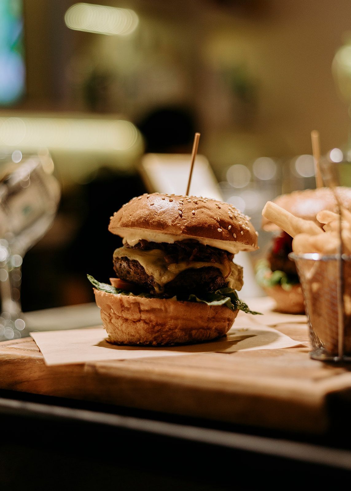 A close up of a hamburger on a wooden cutting board.