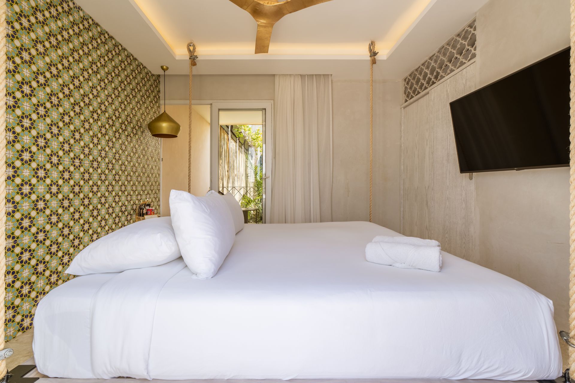 Un dormitorio con una cama king size, televisión y ventilador de techo.