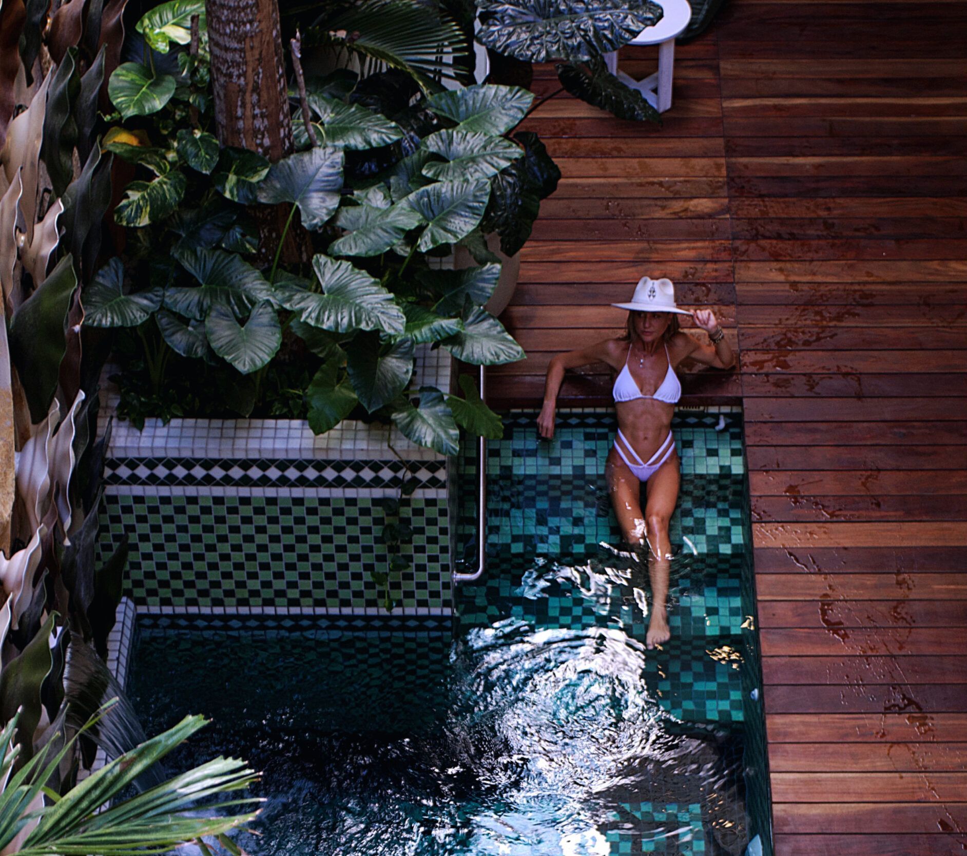 A woman in a bikini is laying on the edge of a swimming pool