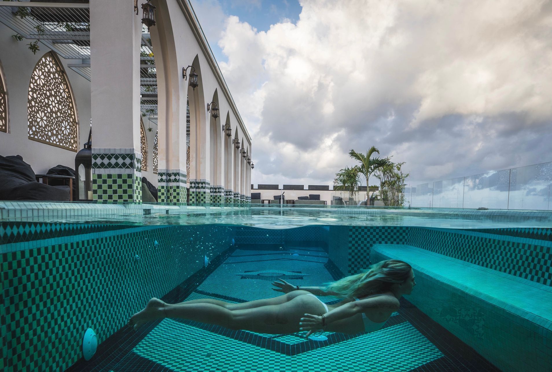 A woman is swimming in a pool with a building in the background.