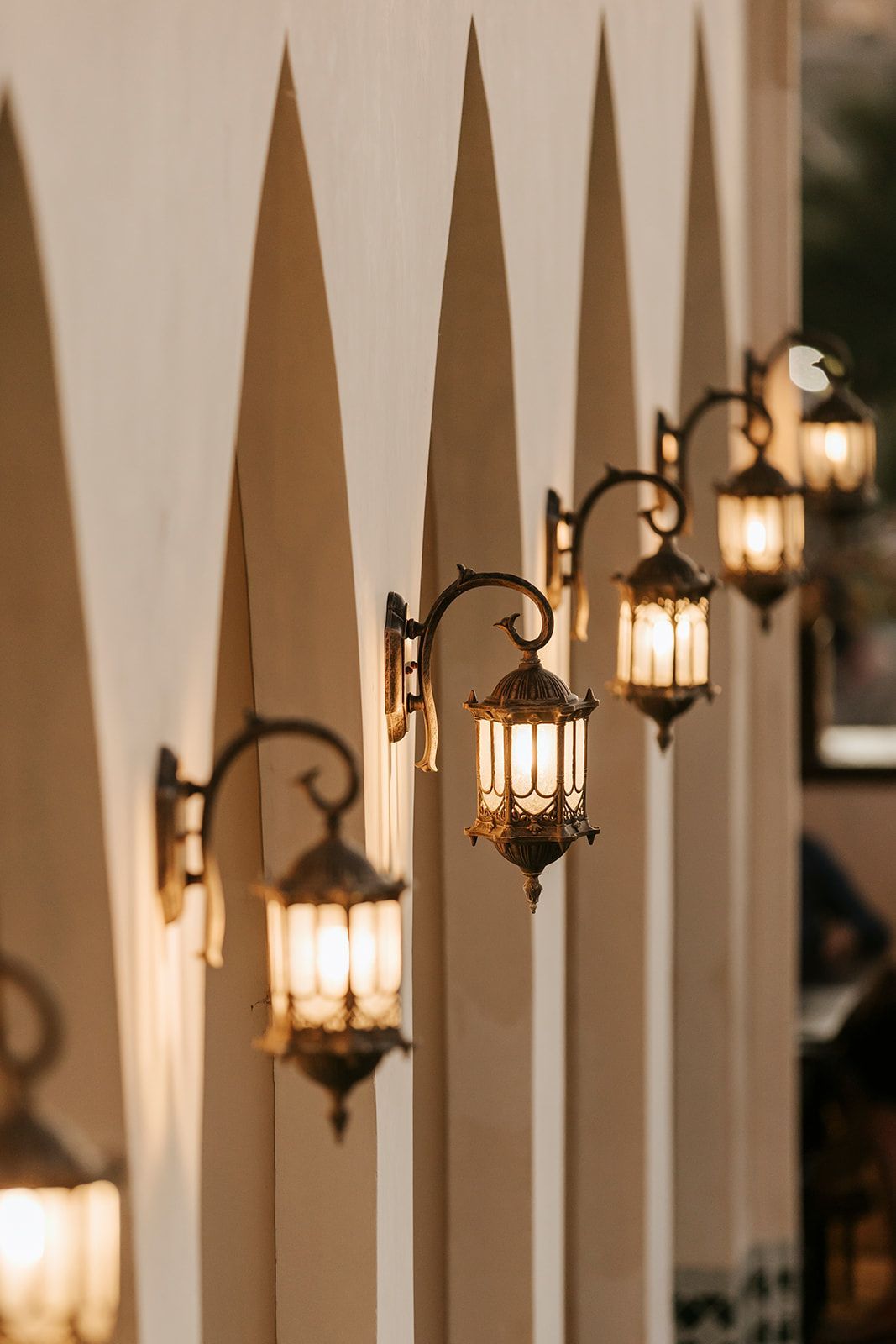 A row of lanterns are hanging on a wall.