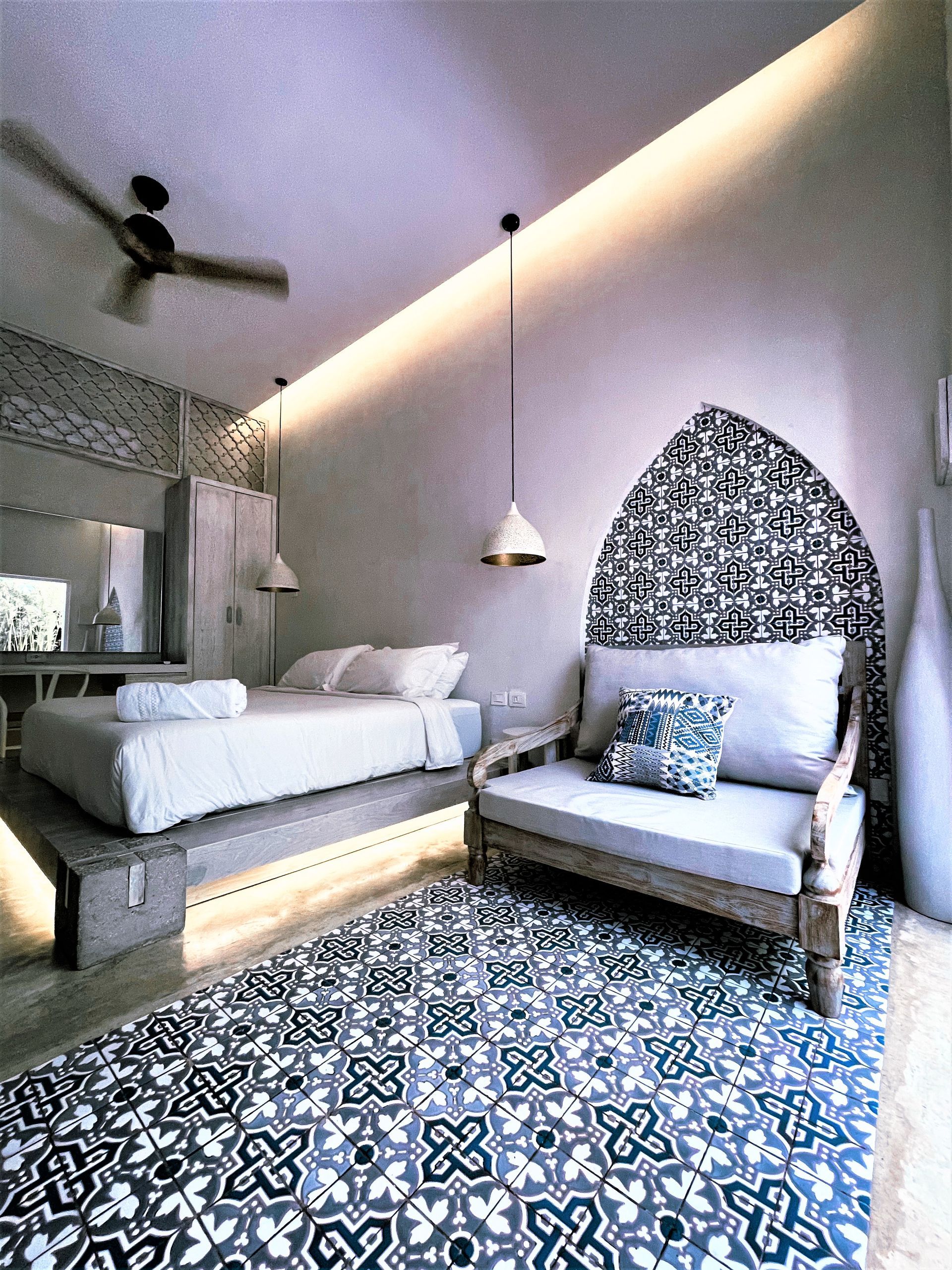 Un dormitorio con una cama, una silla y un ventilador de techo.