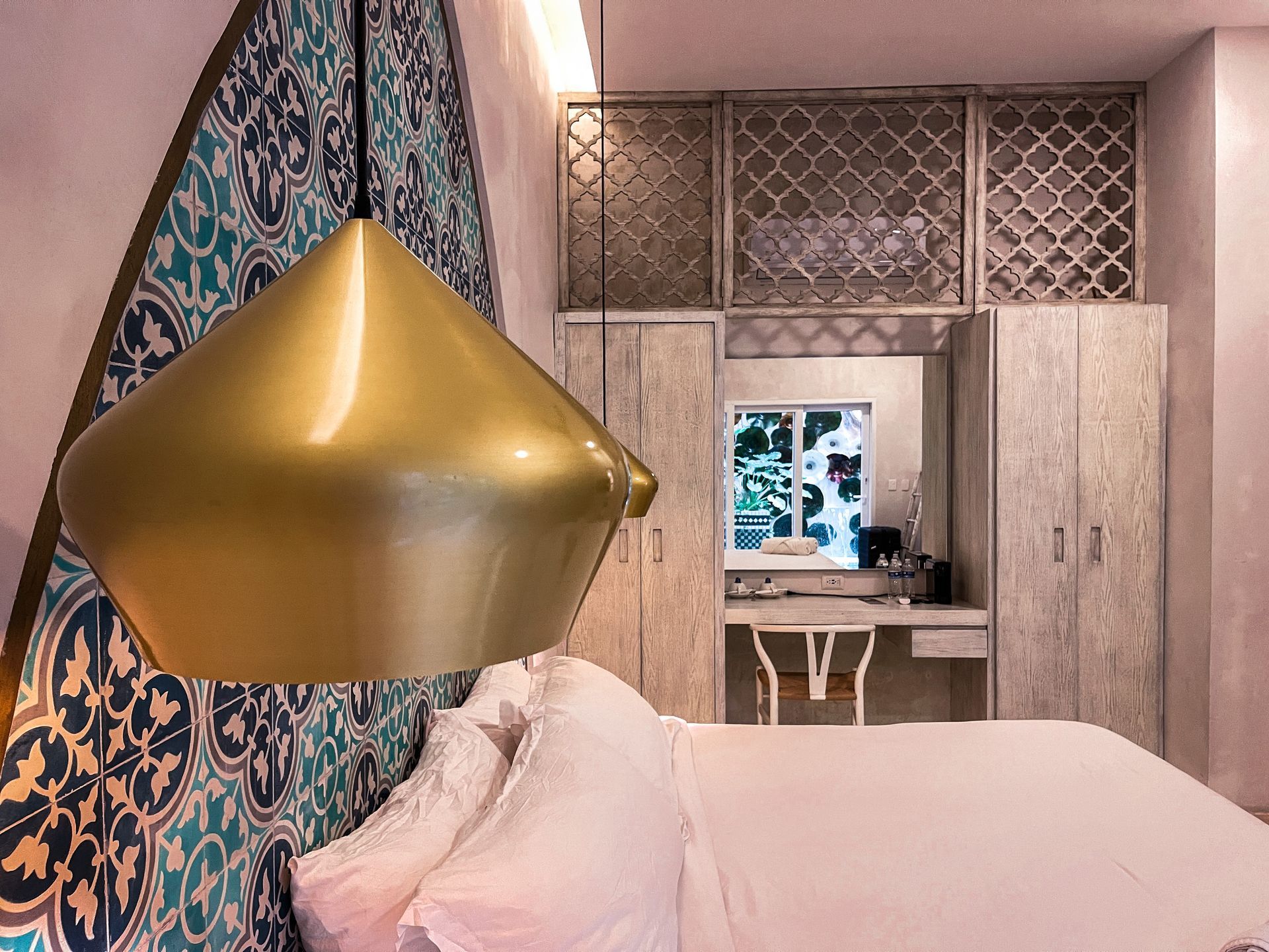 Un dormitorio con una cama, un escritorio y una lámpara colgando del techo.