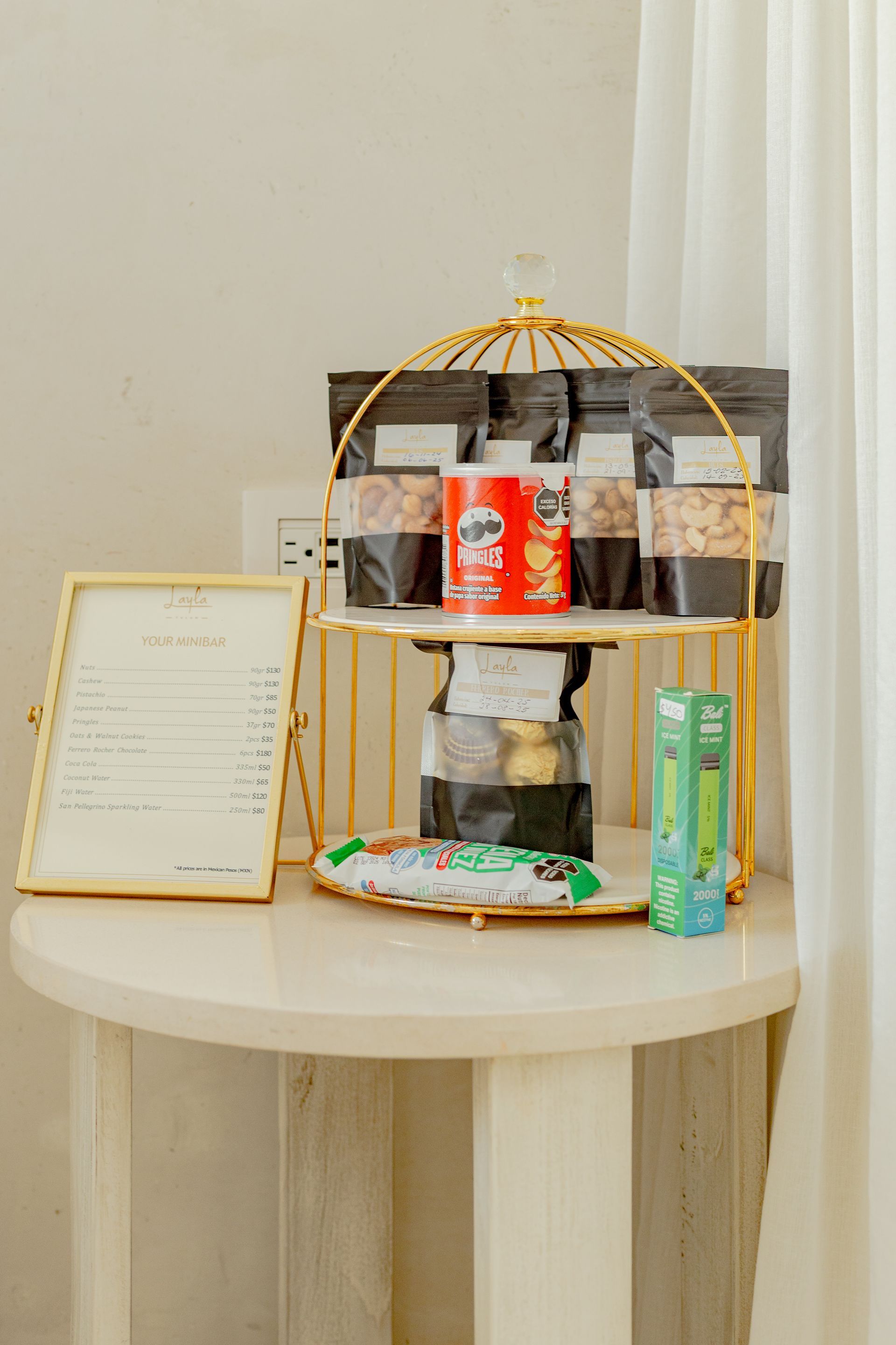 Puesto de snacks dorado con forma de jaula de pájaro, con variedad de snacks, un menú en una mesita 