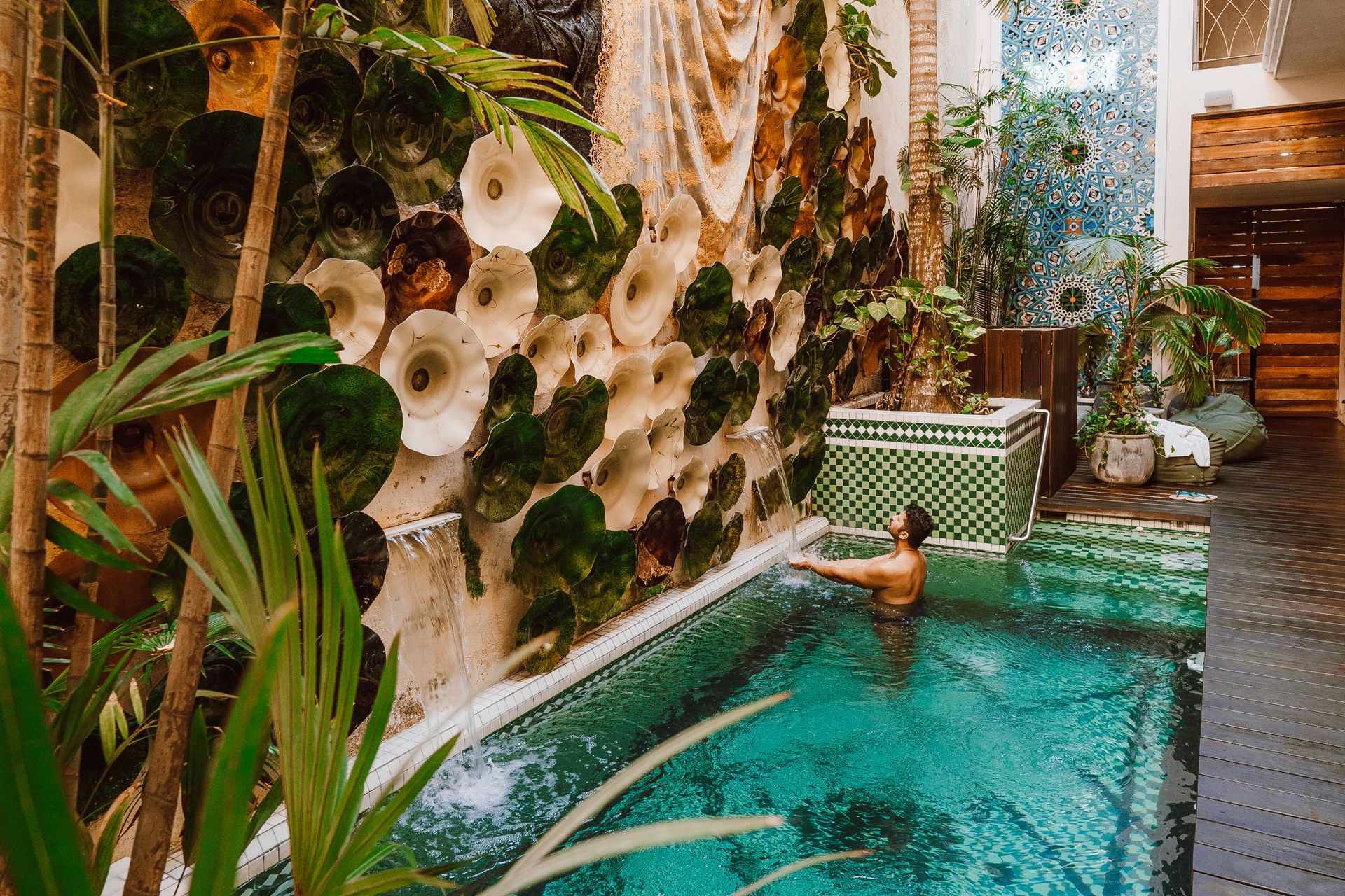A man is swimming in a swimming pool surrounded by plants.