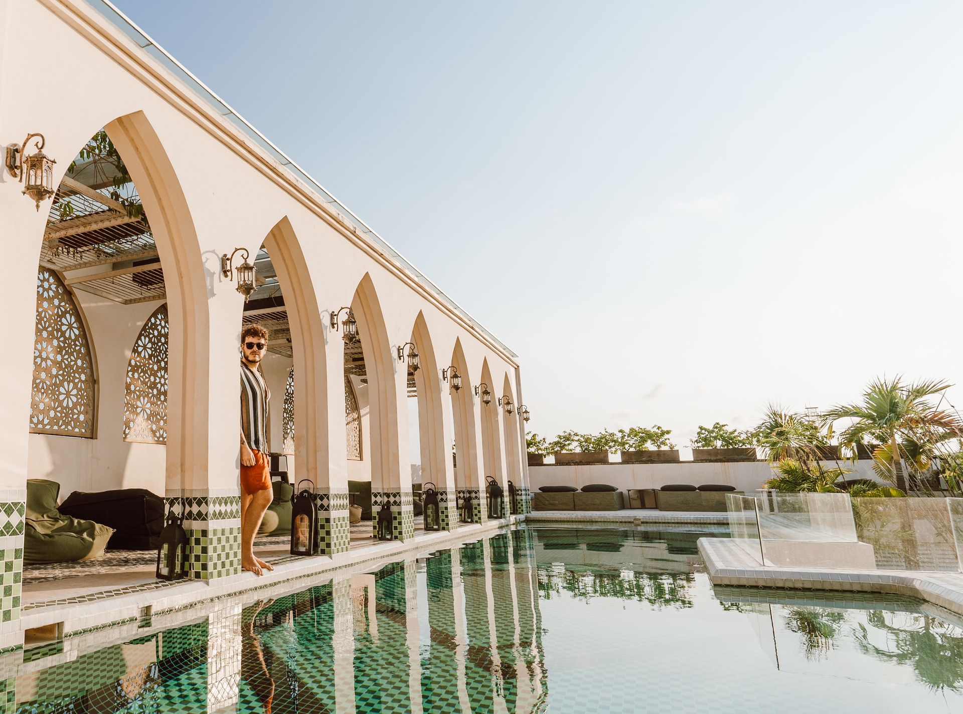 Una mujer está parada junto a una piscina frente a un edificio.