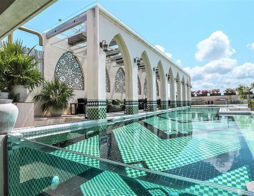 A woman in a bikini is sitting on a couch next to a pool.