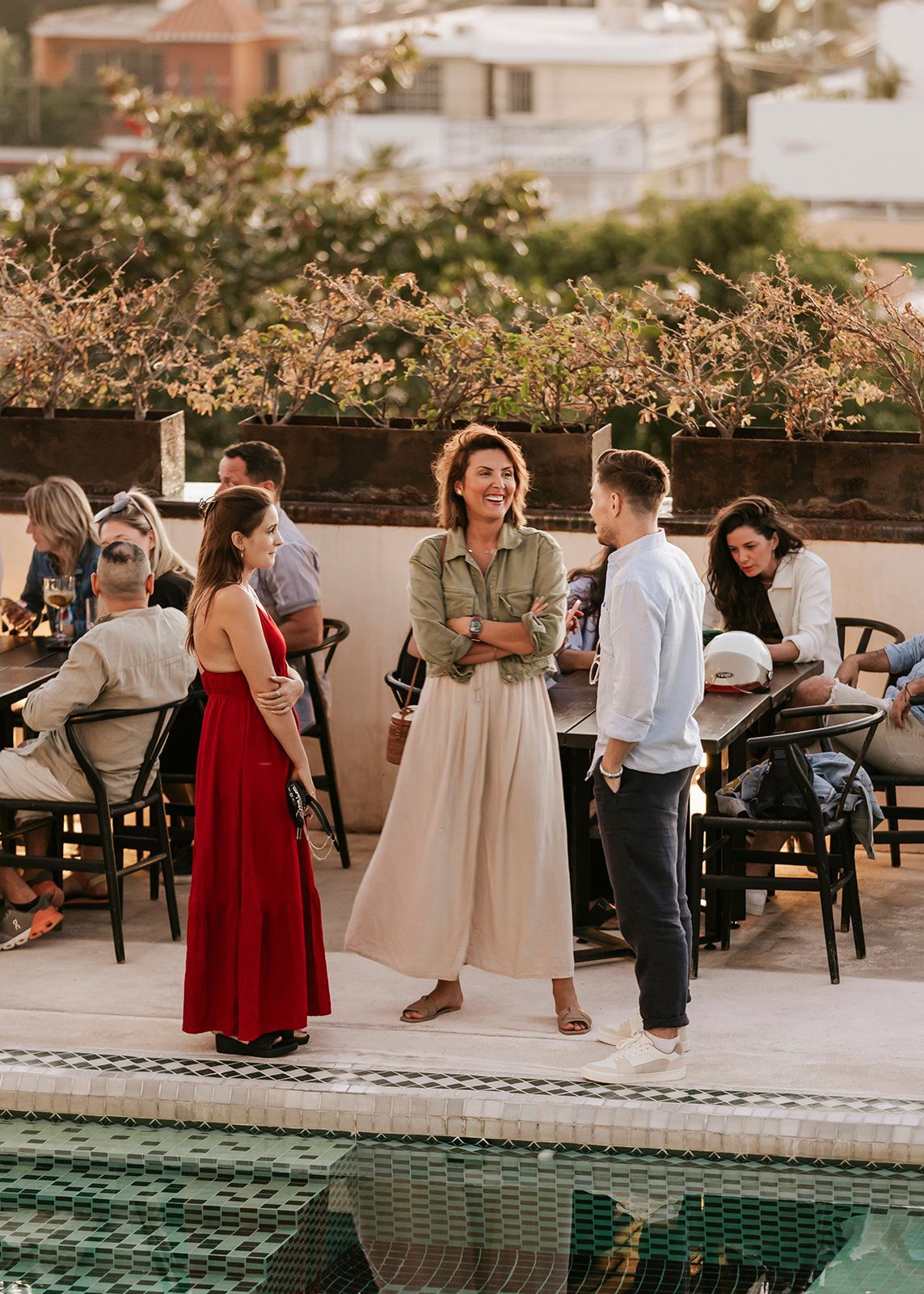 Un grupo de personas están de pie alrededor de una piscina hablando entre sí.