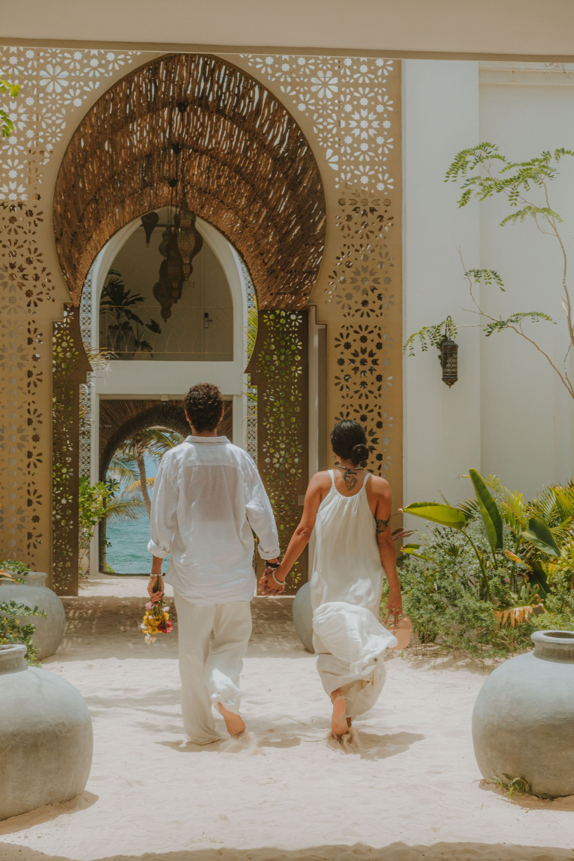 a couple on vacation in Tulum mexico is walking towards the beach club of sana Tulum boutique hotel