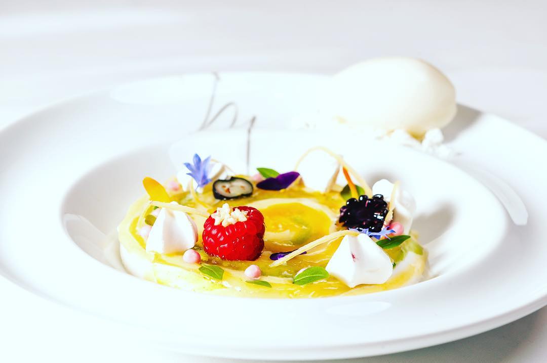 Ein weißer Teller mit Himbeeren, Zitronen und Baiser.