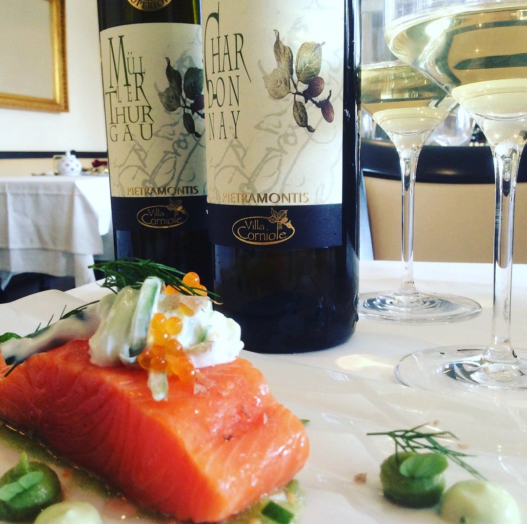 Zwei Flaschen Wein und ein Stück Lachs auf einem Teller