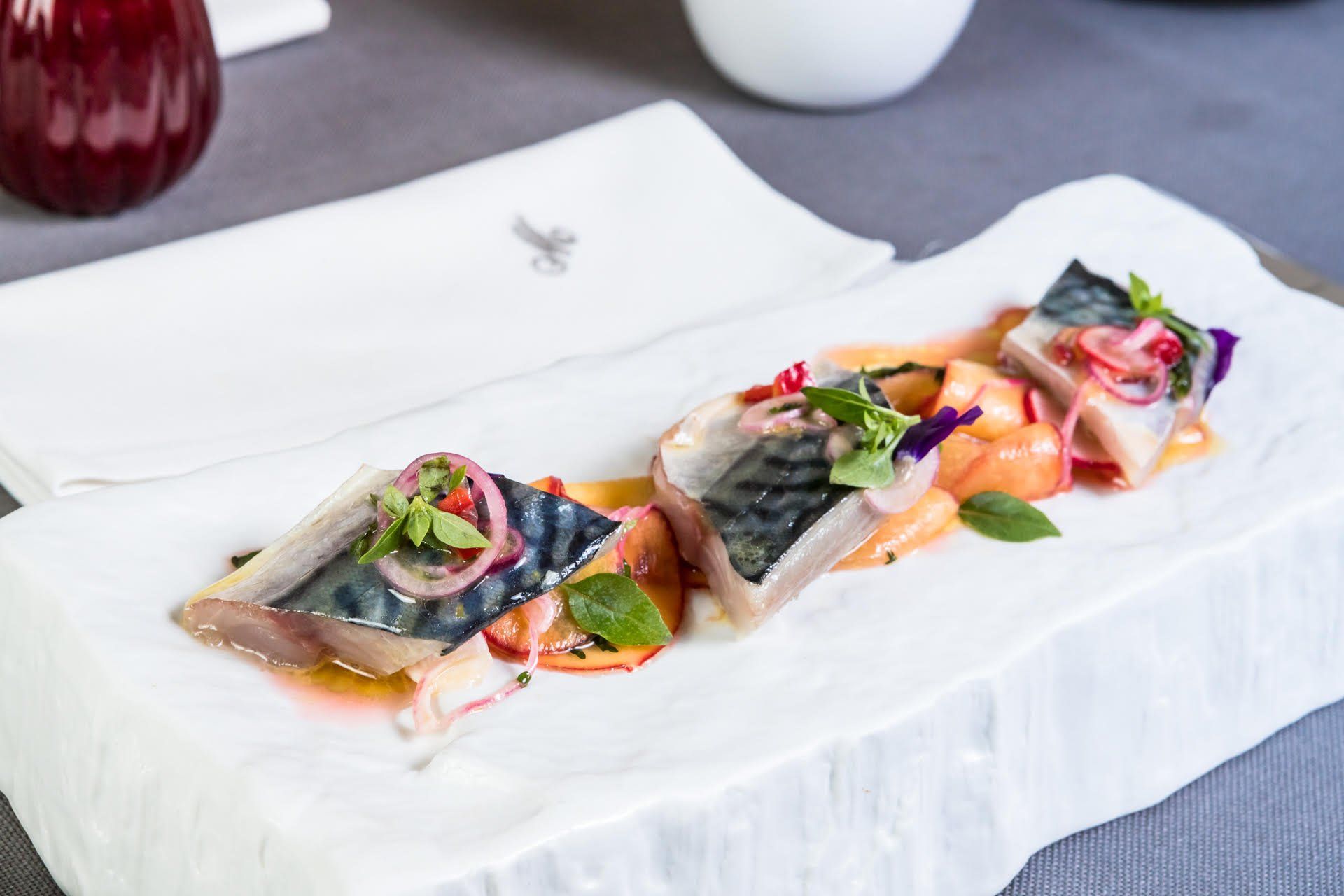 Ein weißer Teller mit Fisch und Gemüse auf einem Tisch.