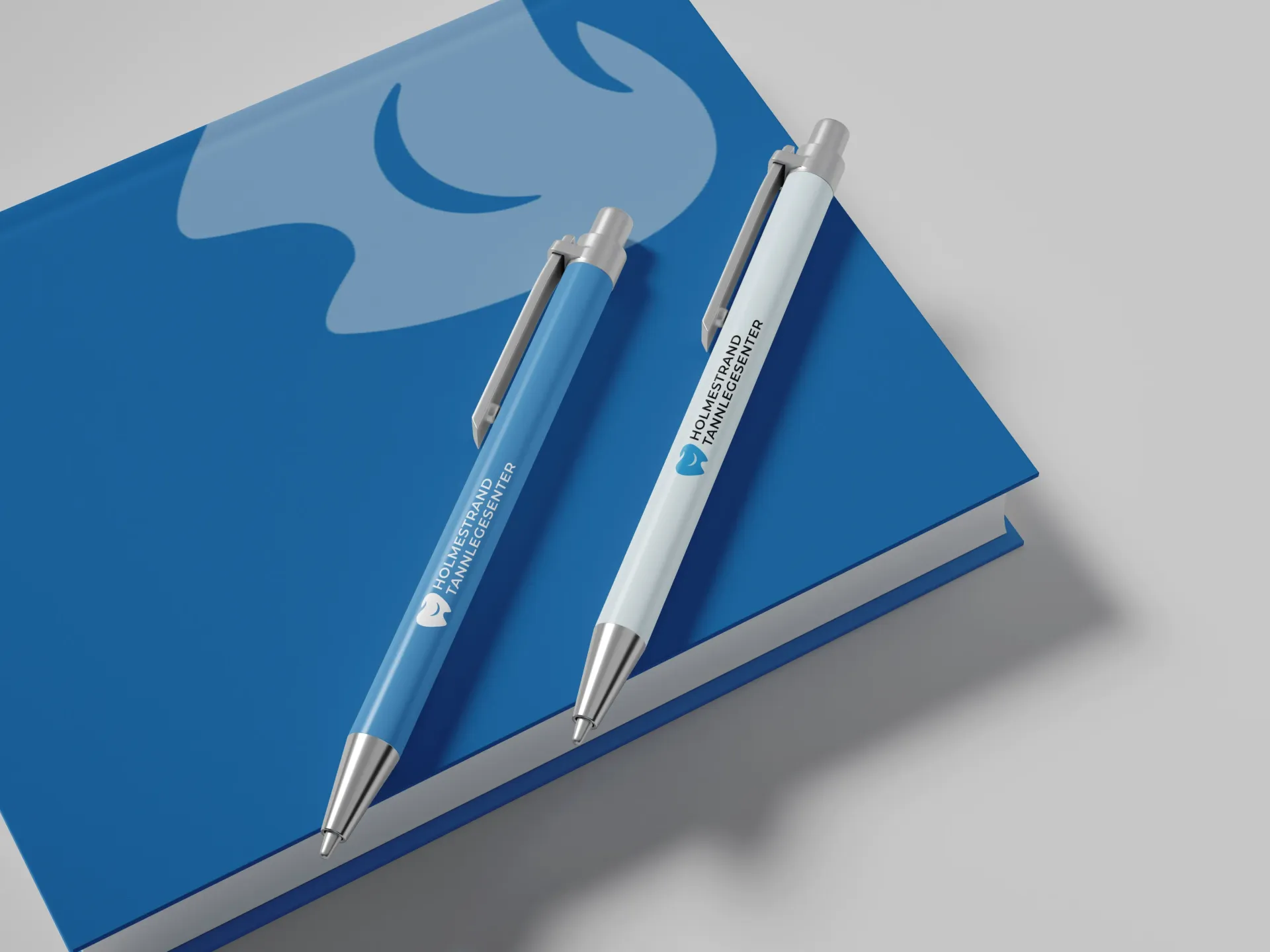 To penner sitter på toppen av en blå notatbok.