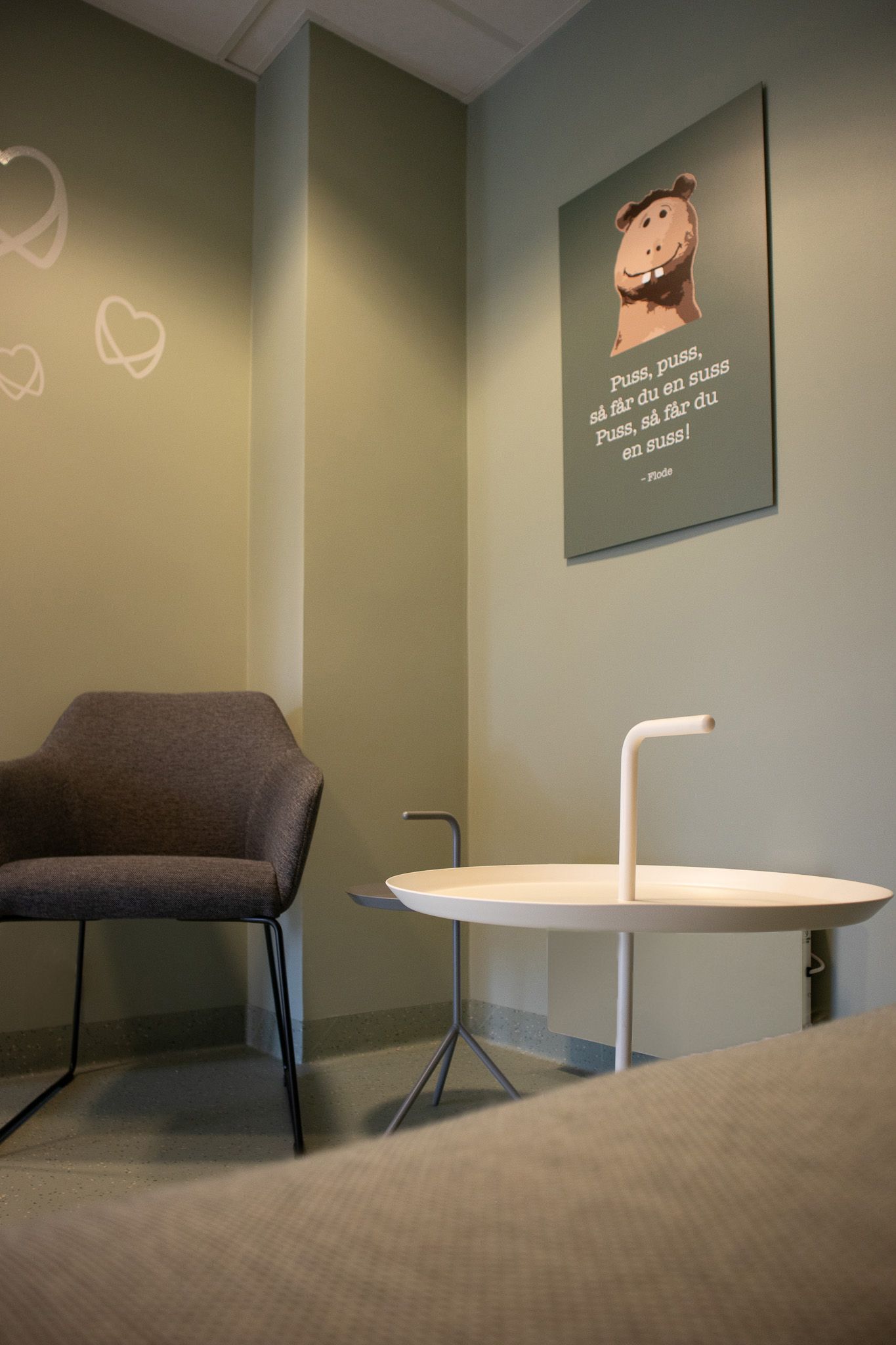 Et venterom med stol og bord og plakat på veggen.