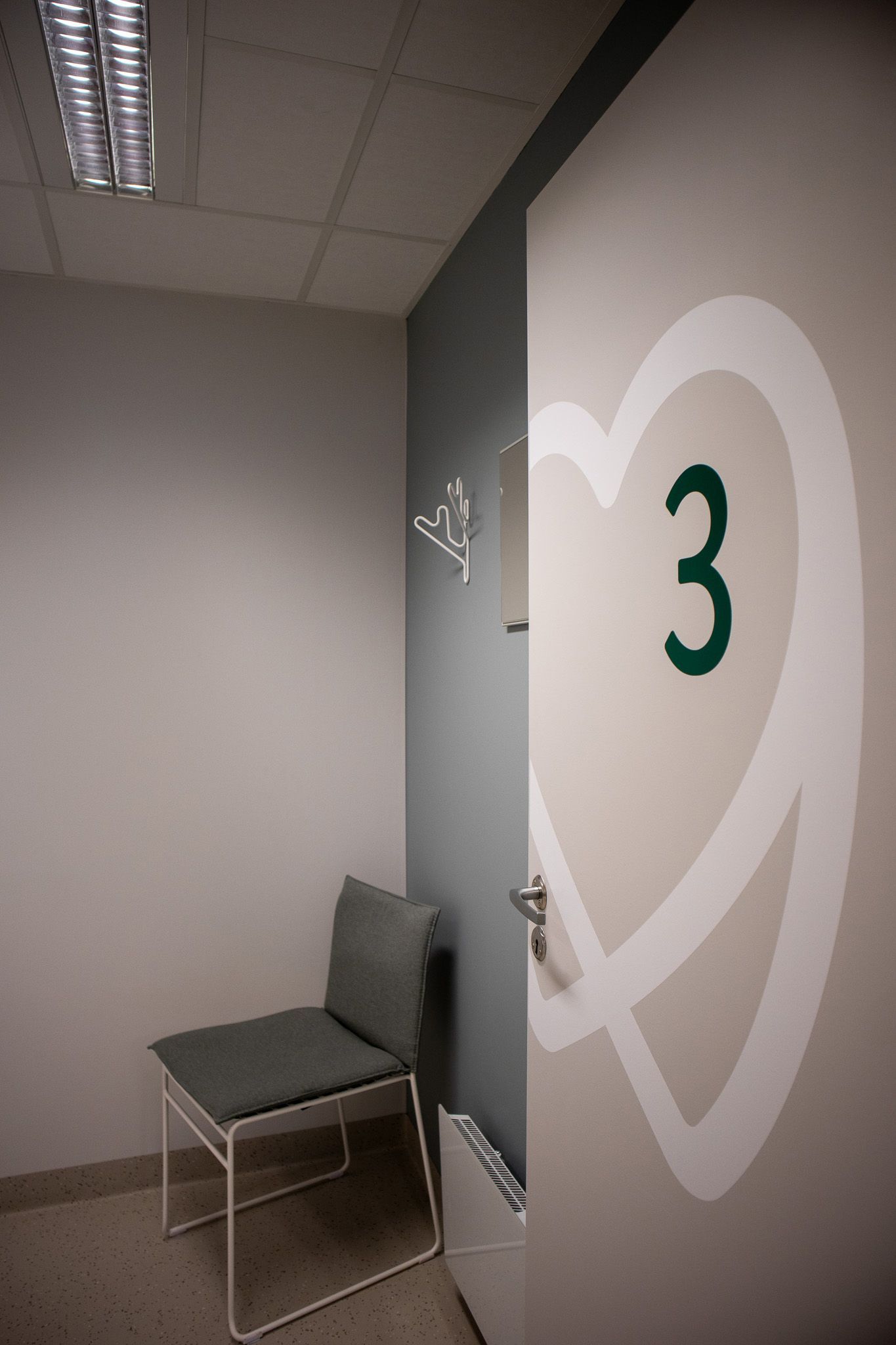 Et venterom med en stol og en dør med 3-tallet på.