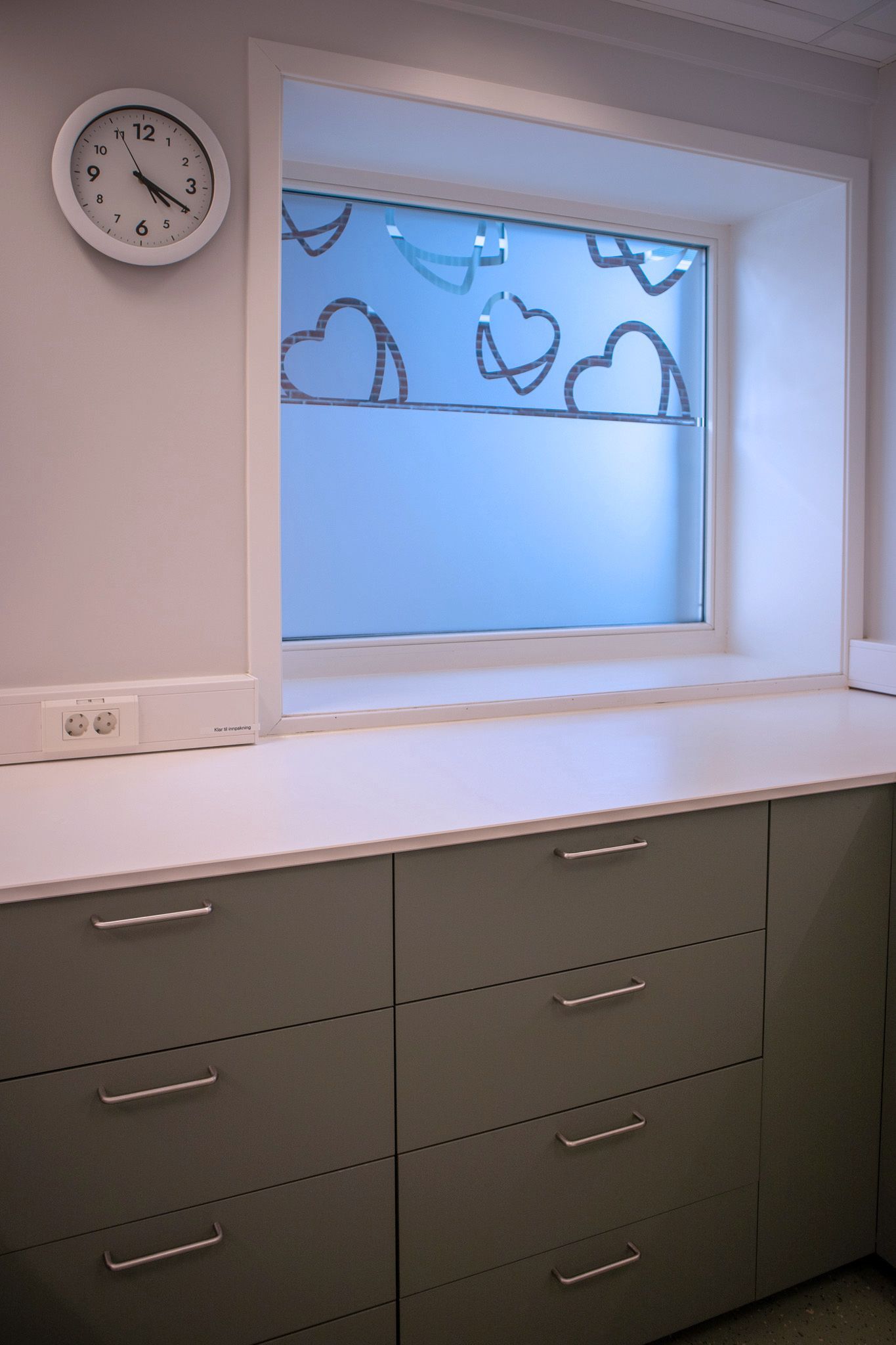 Et kjøkken med vindu og klokke på veggen