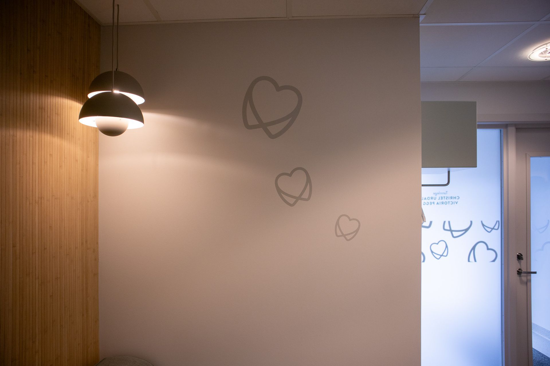 En hvit vegg med hjerter malt på og et lys hengende fra taket.