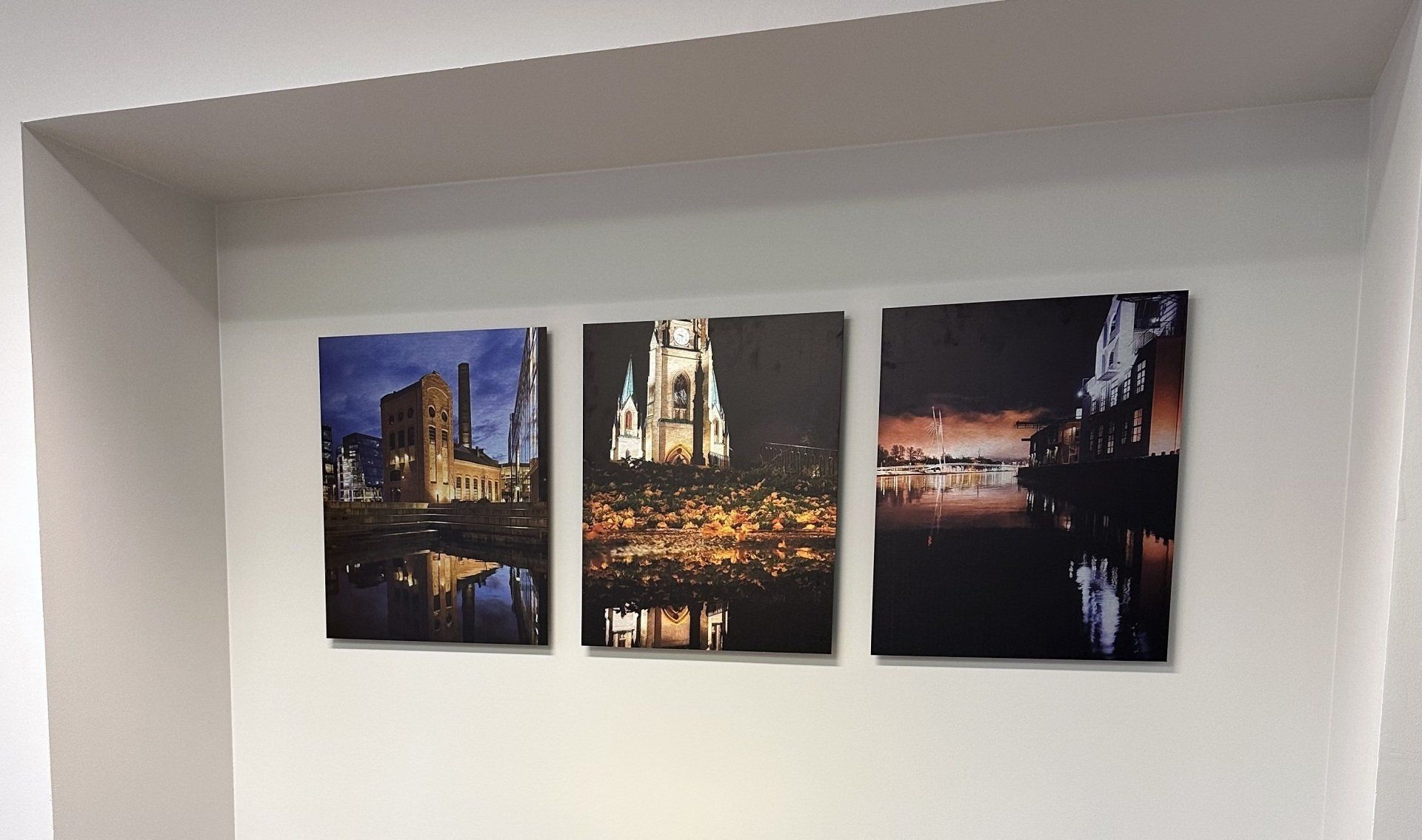 Tre malerier henger på en hvit vegg