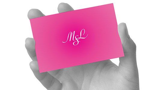 En person holder et rosa visittkort i hånden.