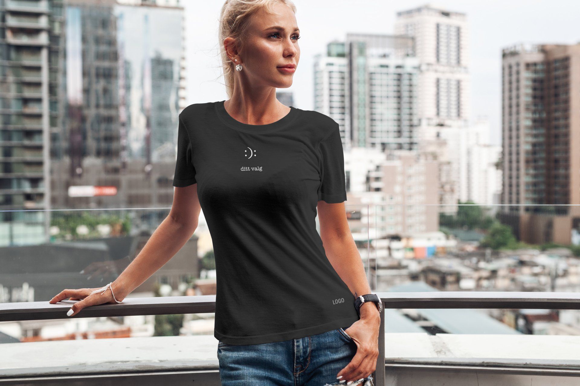 En kvinne står på en balkong iført en svart t-skjorte med et smilefjes på.