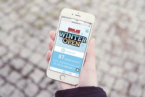 En person holder en mobiltelefon som sier vinter Open på skjermen.