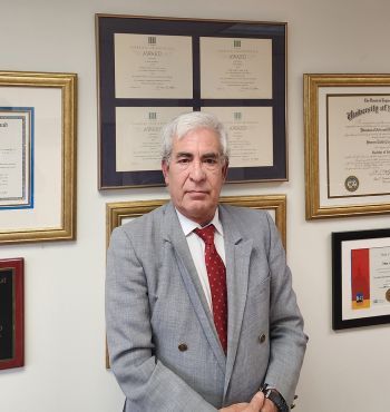 A man in a suit and tie is standing in front of a wall with pictures on it.