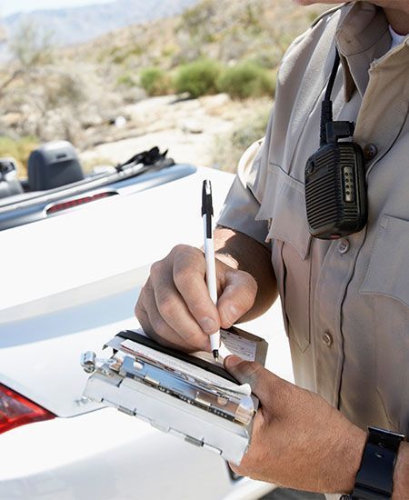 A man wearing a walkie talkie is writing on a clipboard