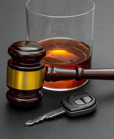 A wooden gavel next to a car key and a glass of alcohol