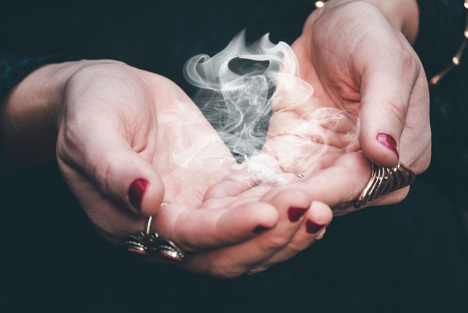 A woman is holding something in her hands with smoke coming out of it.