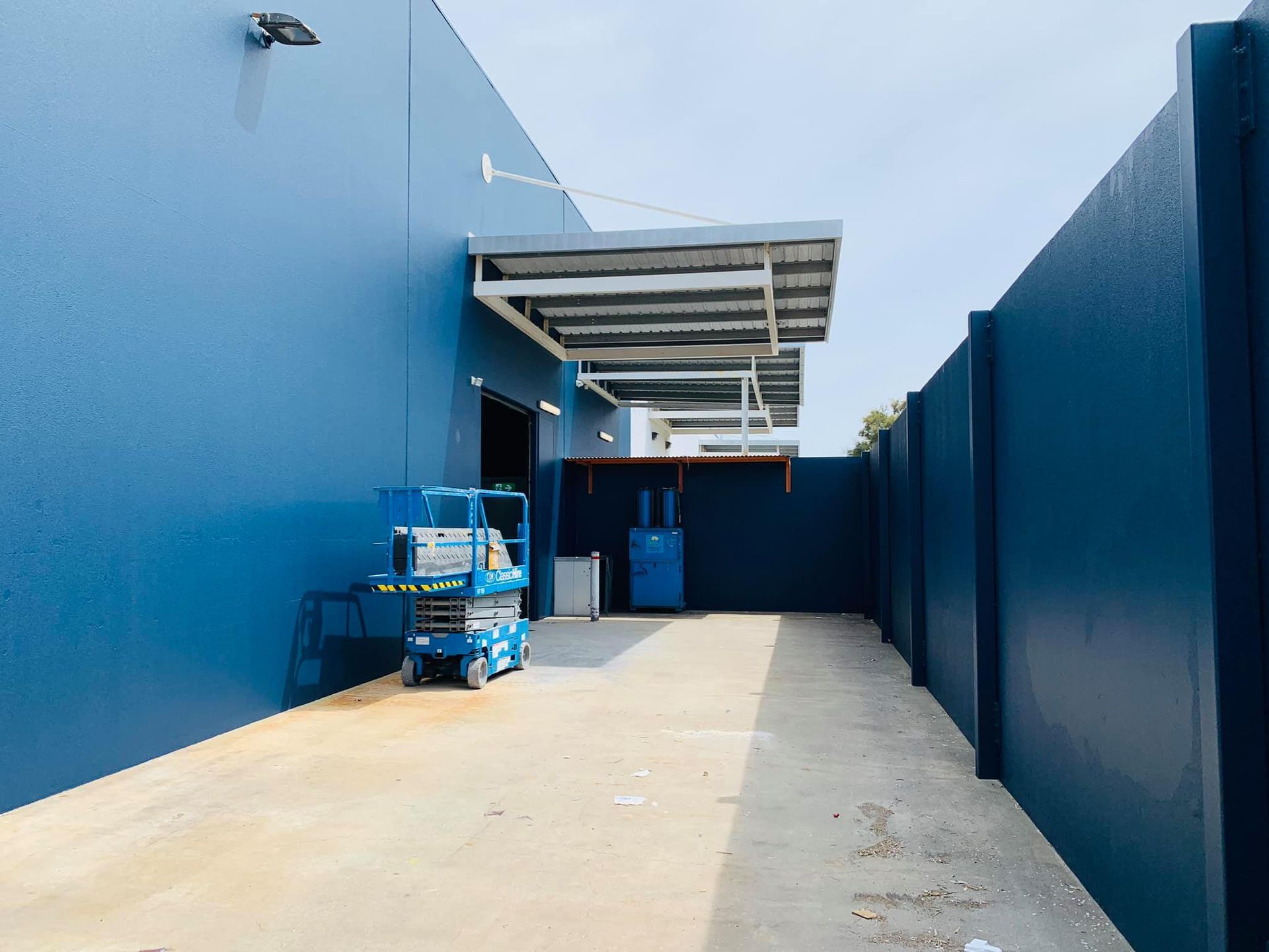 A blue building with a blue fence and a blue lift in front of it.