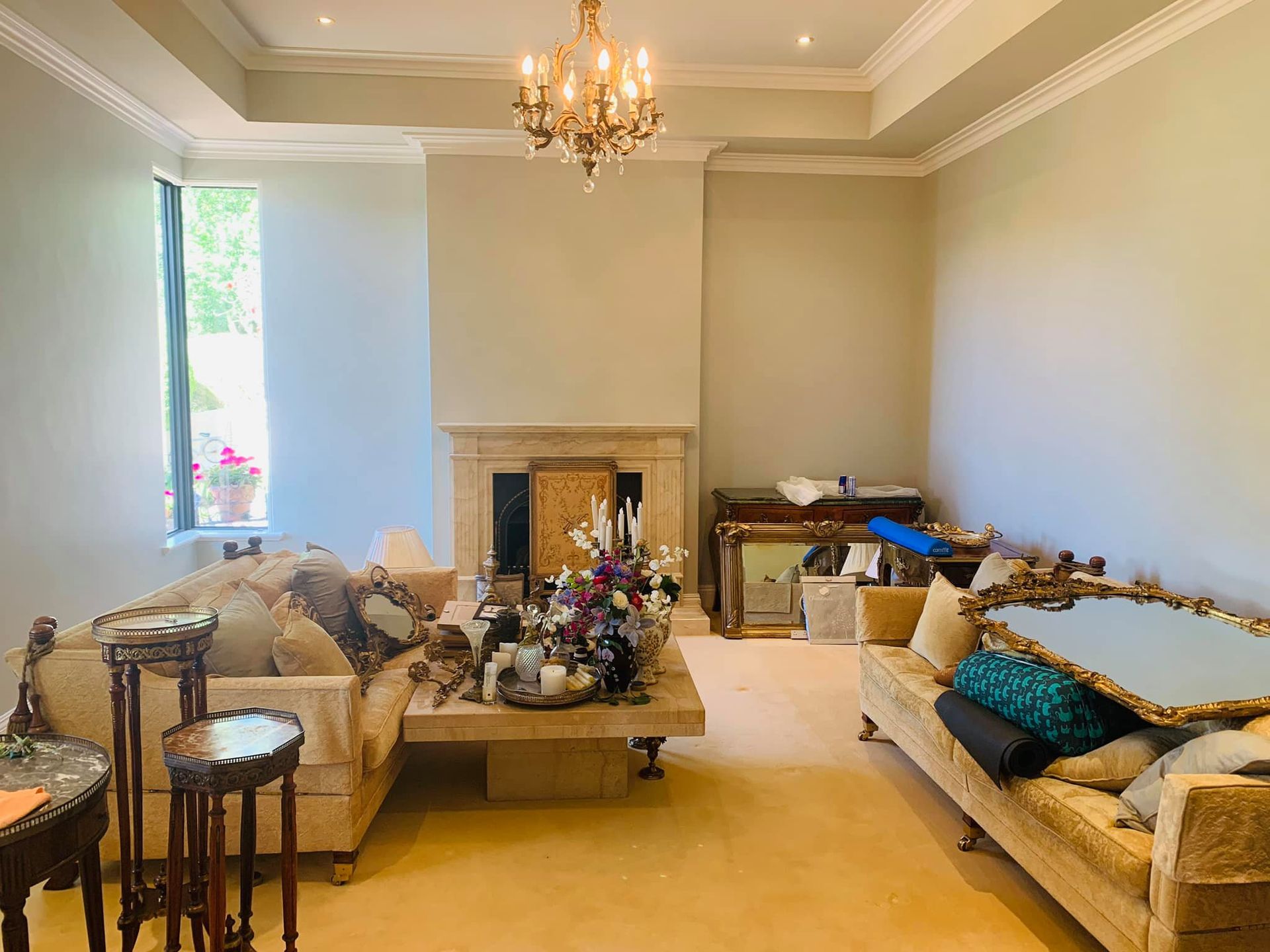 A living room with a couch , table , fireplace and chandelier.