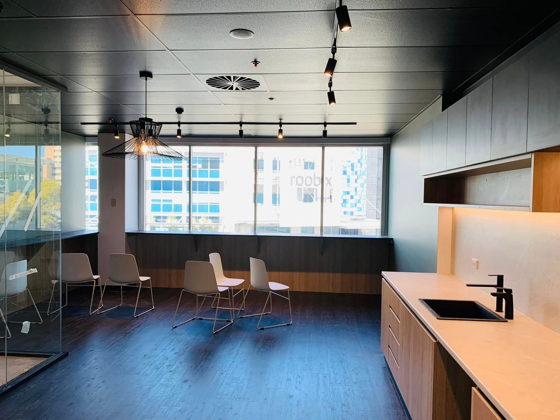 A kitchen with a sink , chairs , and a large window.