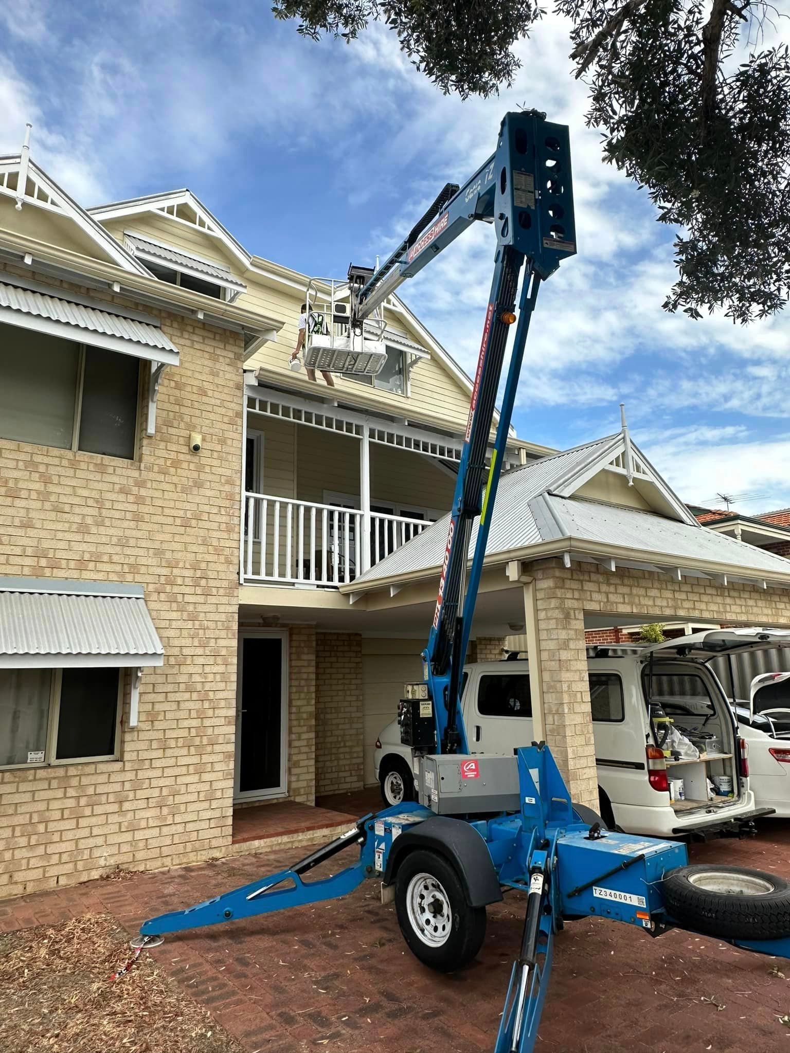 A crane is parked in front of a large house.