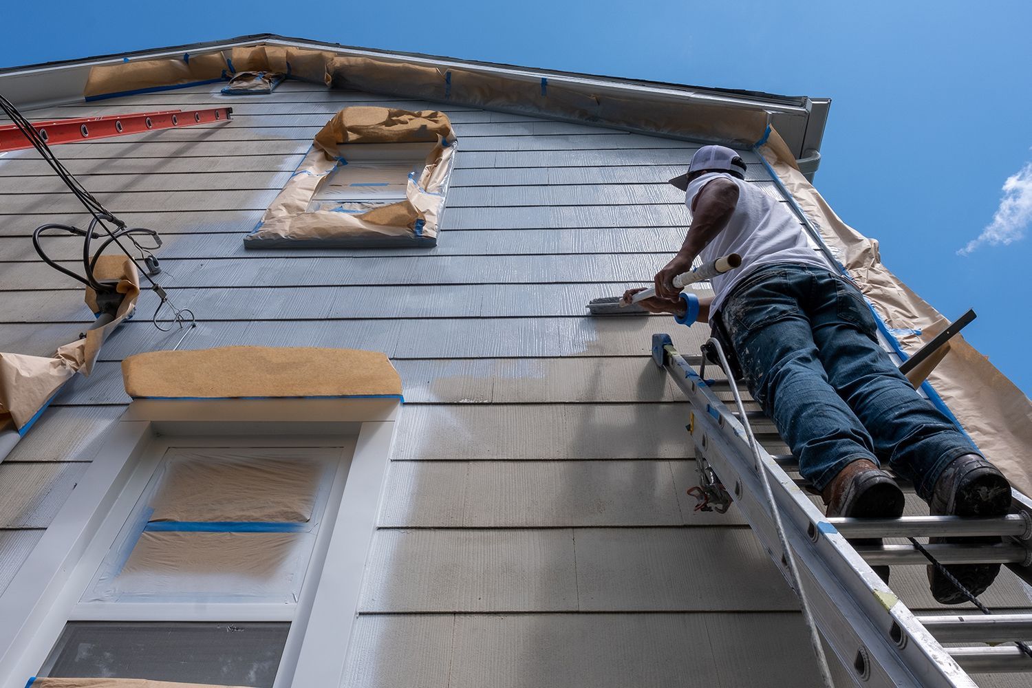 Professional painter applying fresh coat of paint to a home’s exterior.