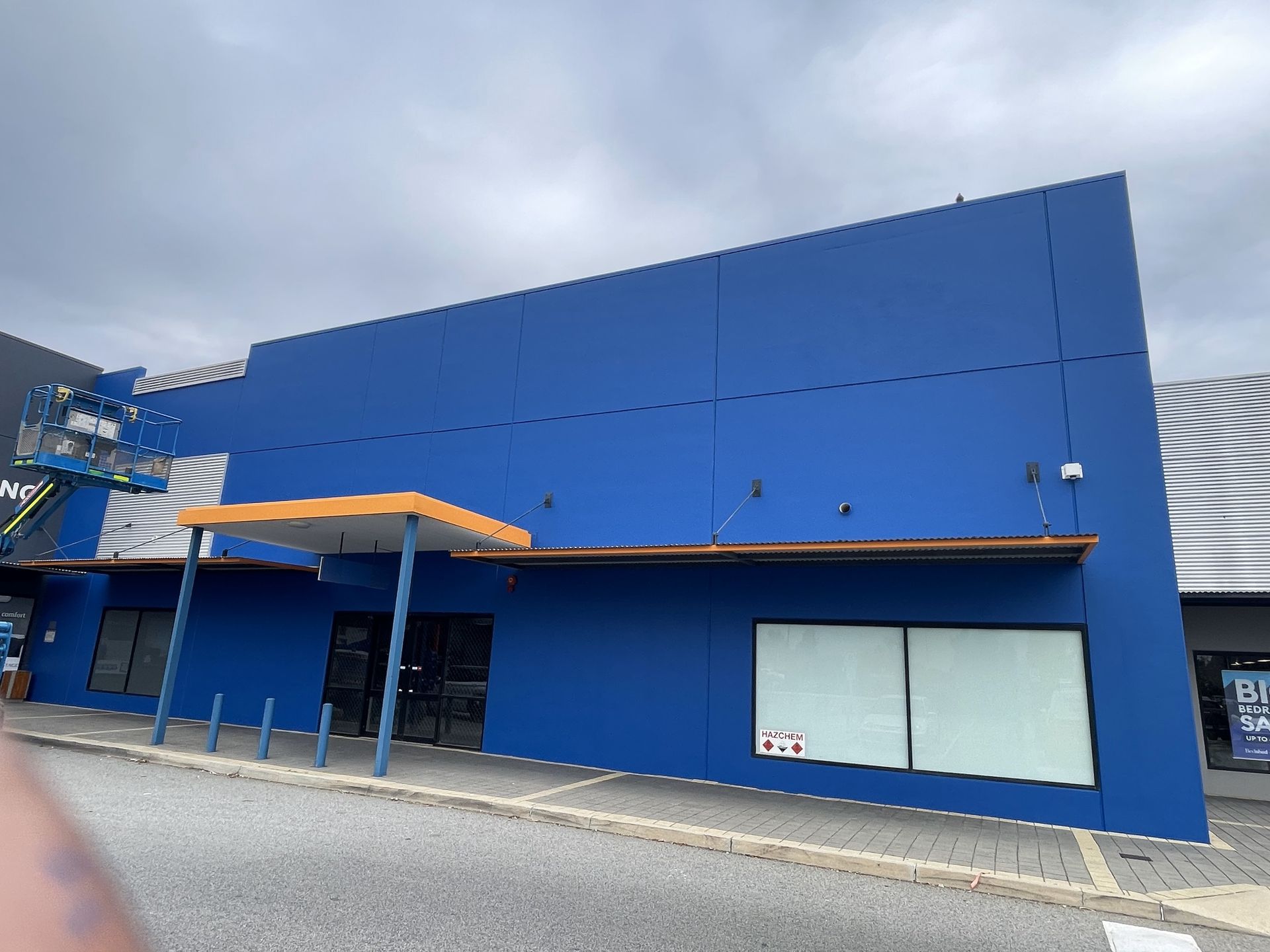 Blue building with an orange awning under a cloudy sky.