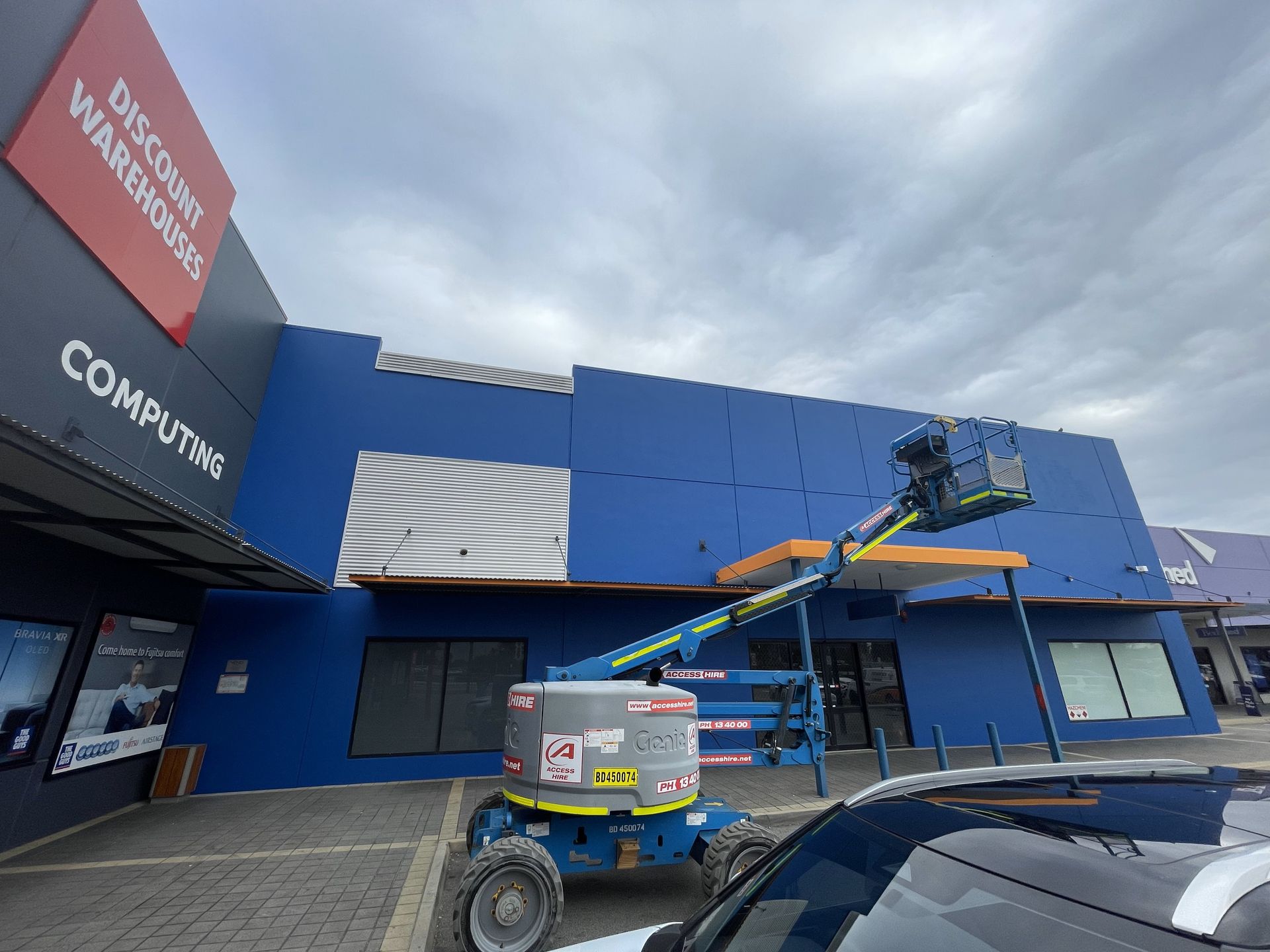 Blue building exterior with a lift platform. Sign reads 