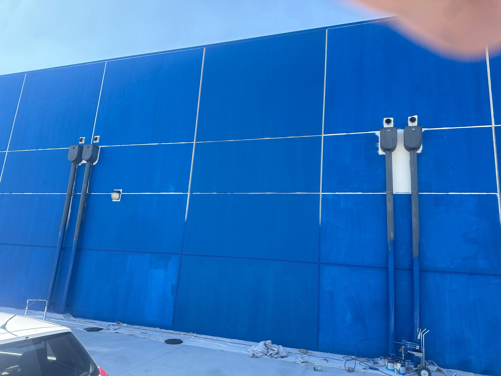 Blue building exterior with white lines, two sets of attached utility fixtures, and snow on the ground.