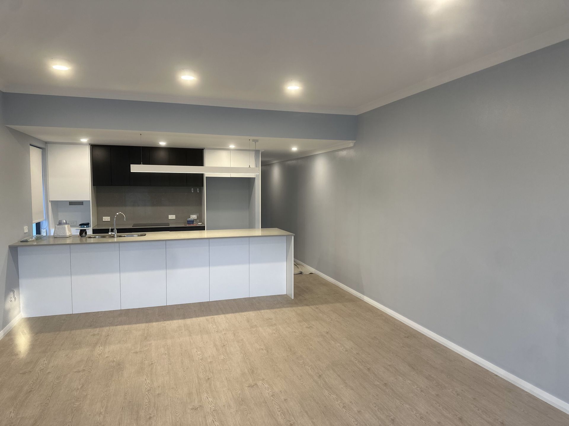 Modern kitchen with white cabinets, gray walls, and wood-look flooring.