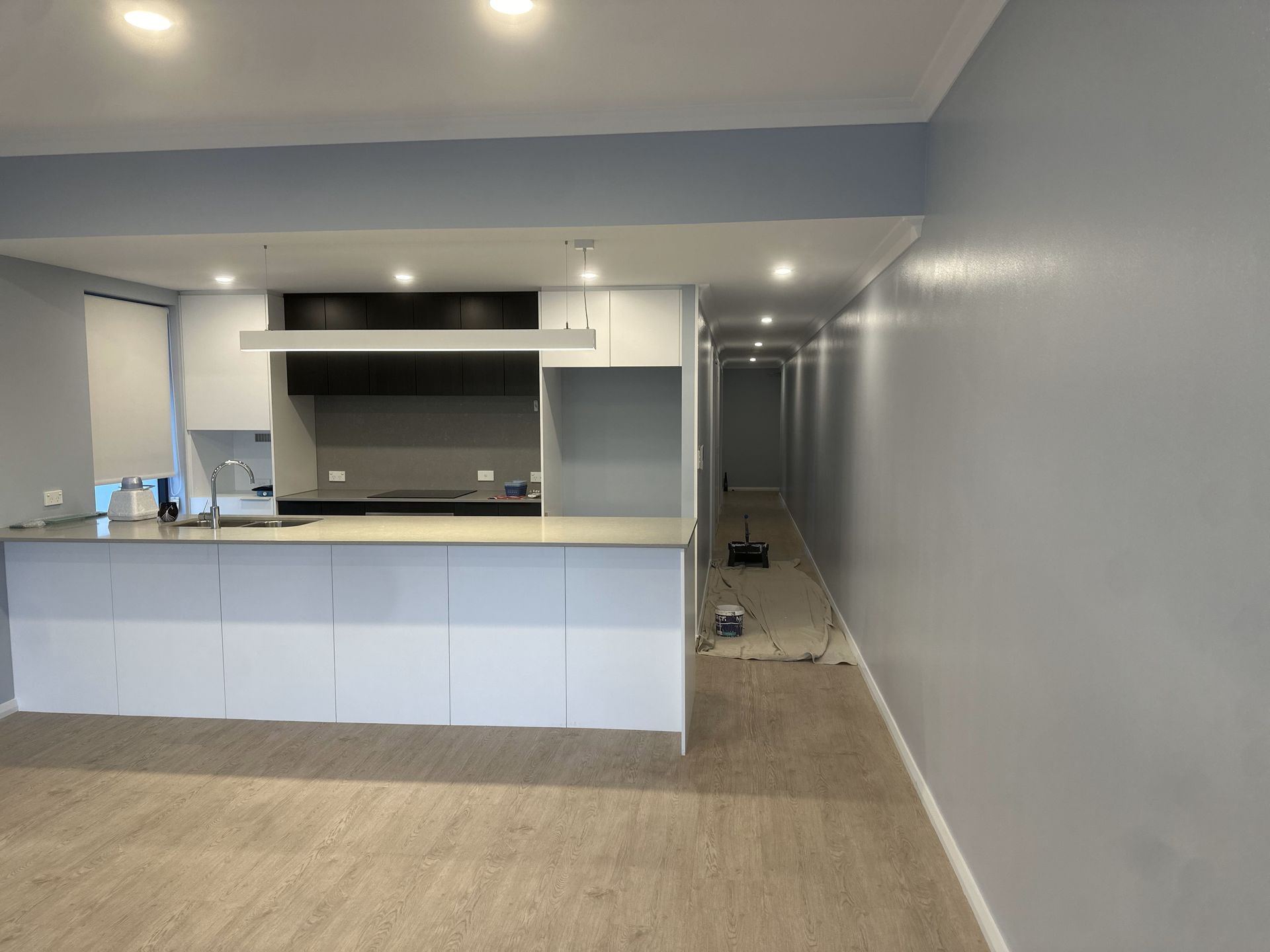 Modern kitchen with white cabinets, gray countertops, and blue walls.