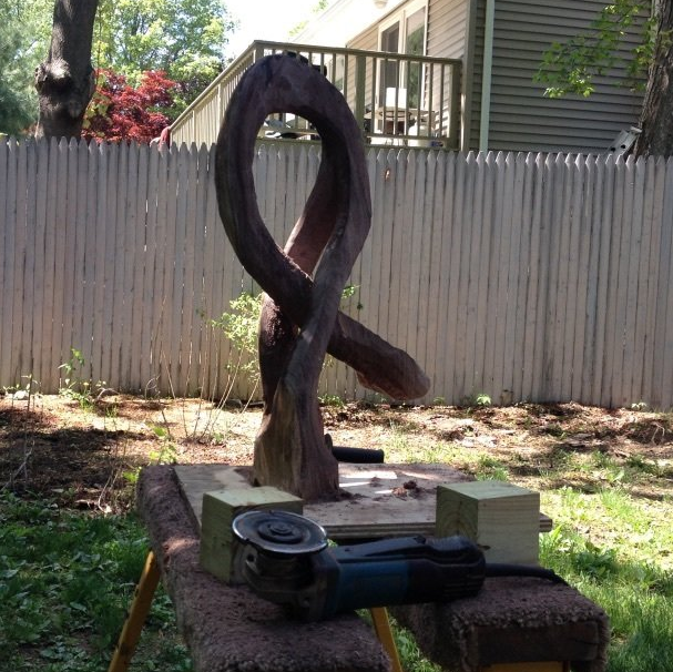 A sculpture is being worked on in a backyard with a fence in the background