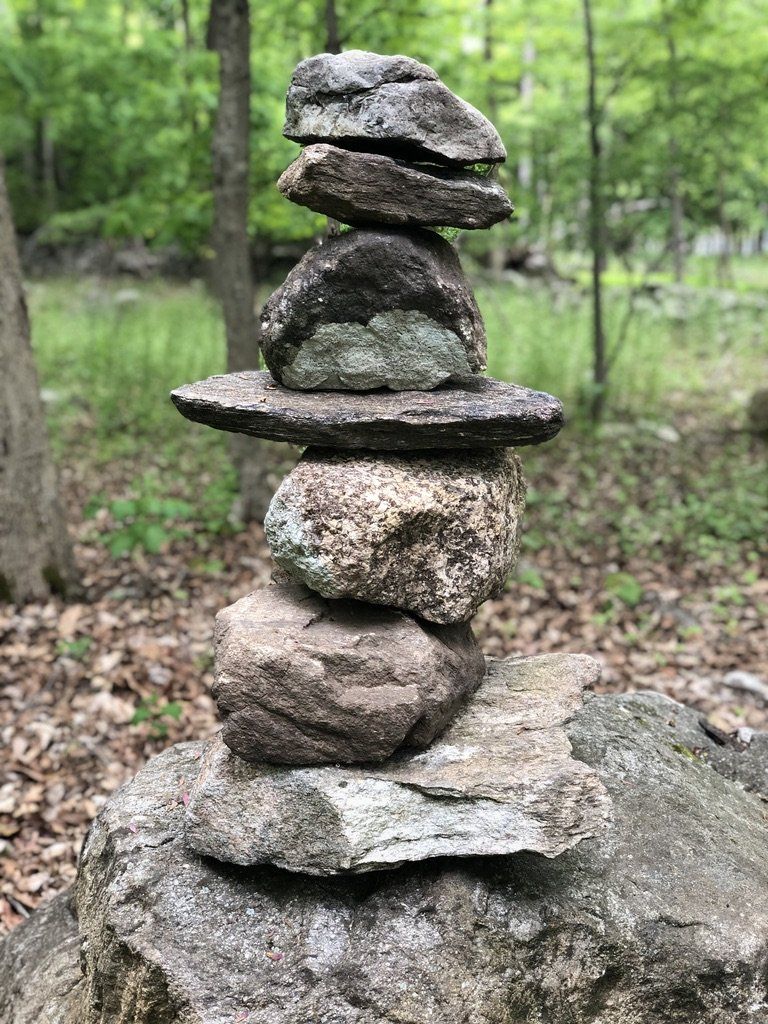 A pile of rocks stacked on top of each other on top of a rock in the woods.