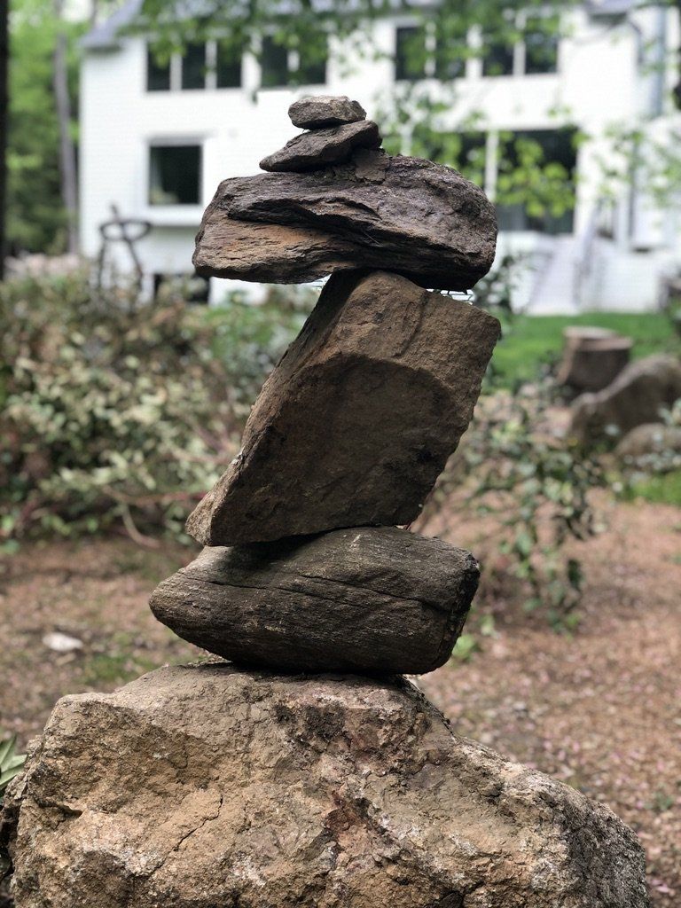 A pile of rocks stacked on top of each other in front of a white house.