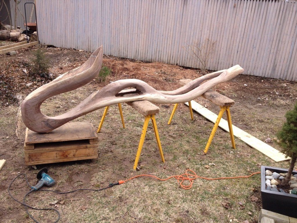 A large piece of wood is sitting on top of a wooden table in a yard.